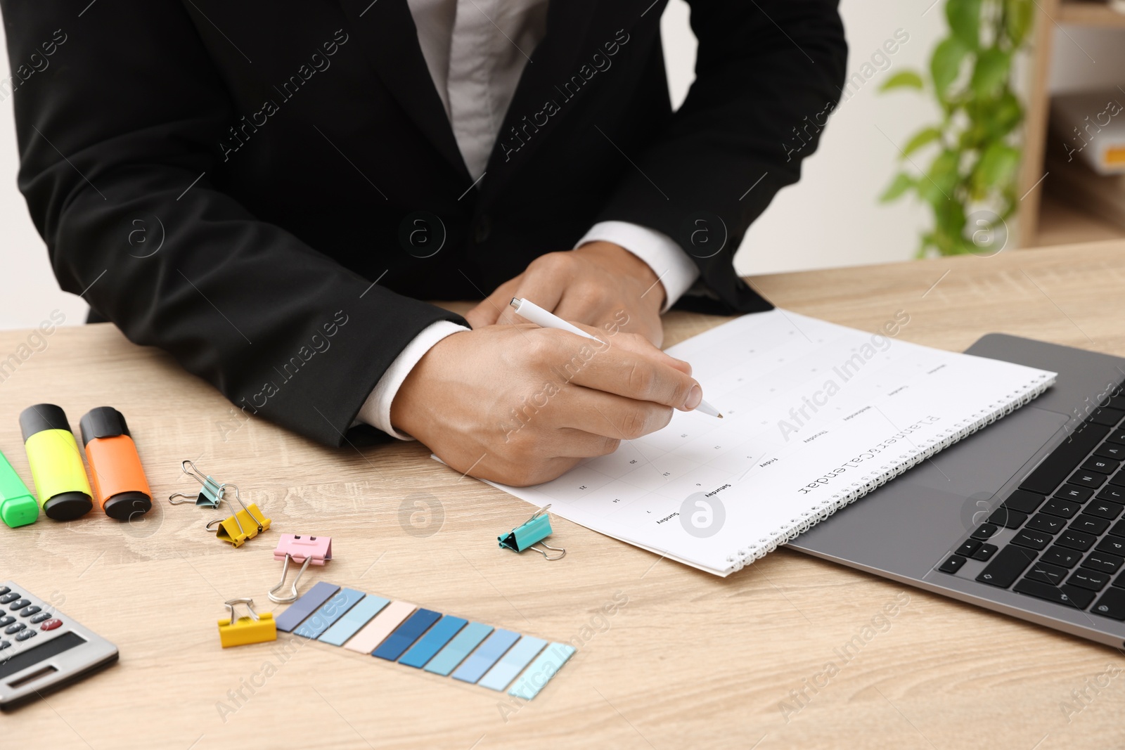 Man using business planner at wooden table in office, closeup Photo of Man using business planner at wooden table in office, closeup