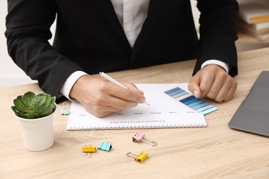 Photo of Man using business planner at wooden table in office, closeup