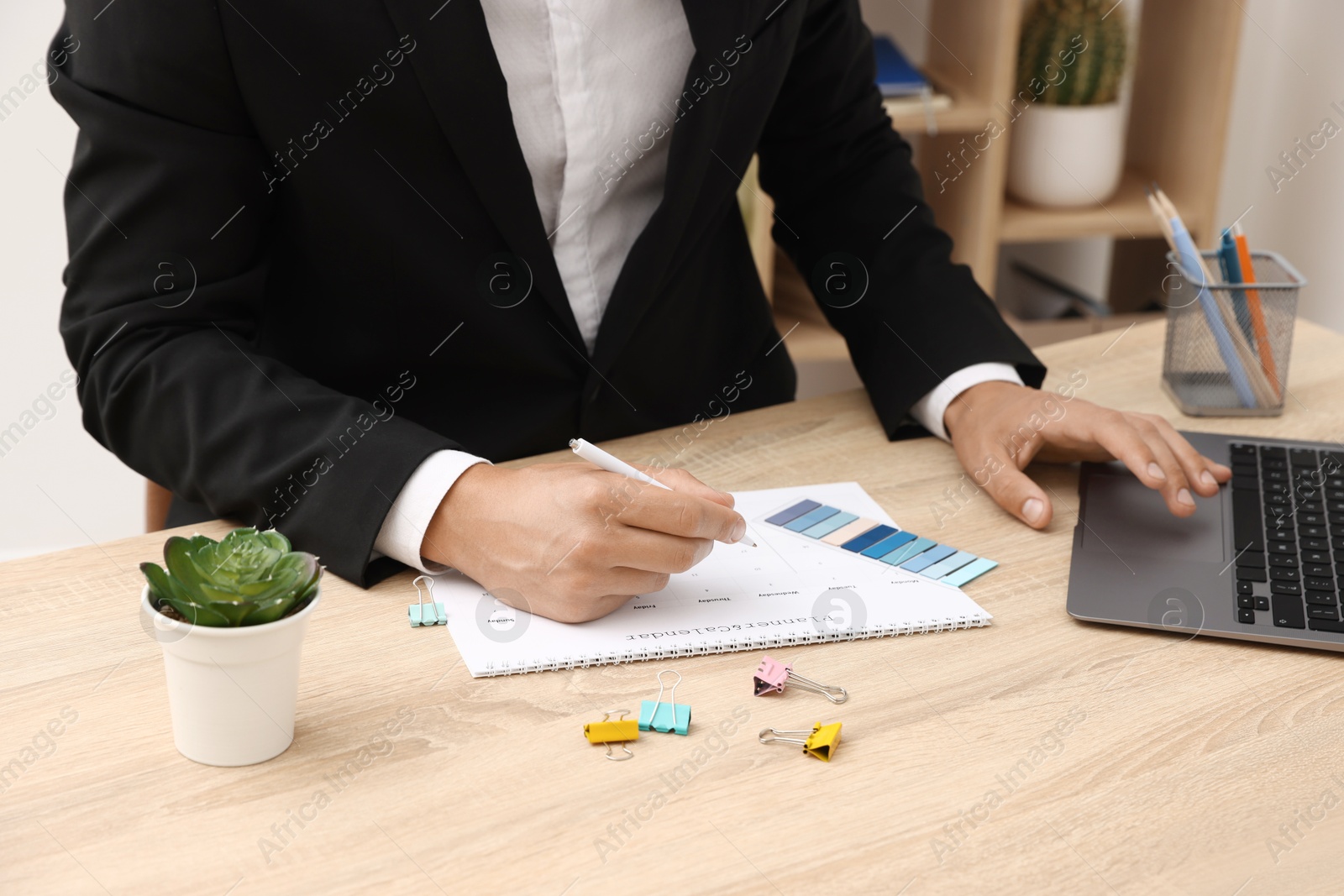Man using business planner at wooden table in office, closeup Photo of Man using business planner at wooden table in office, closeup