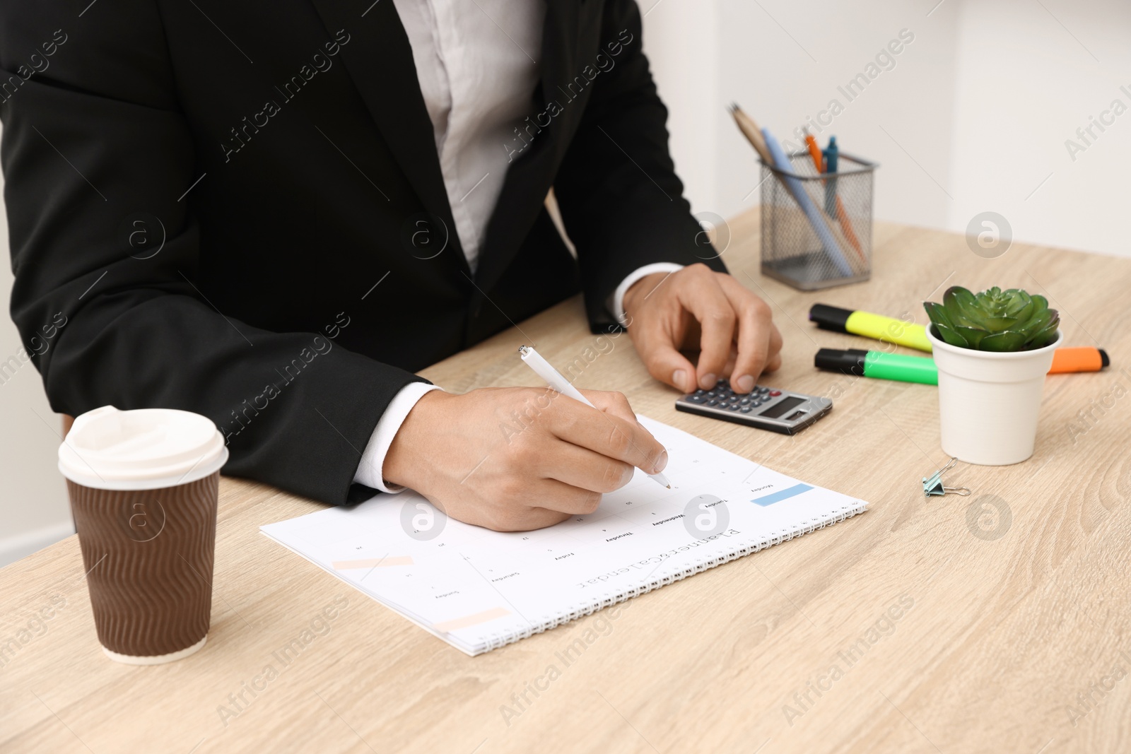 Man using business planner at wooden table in office, closeup Photo of Man using business planner at wooden table in office, closeup