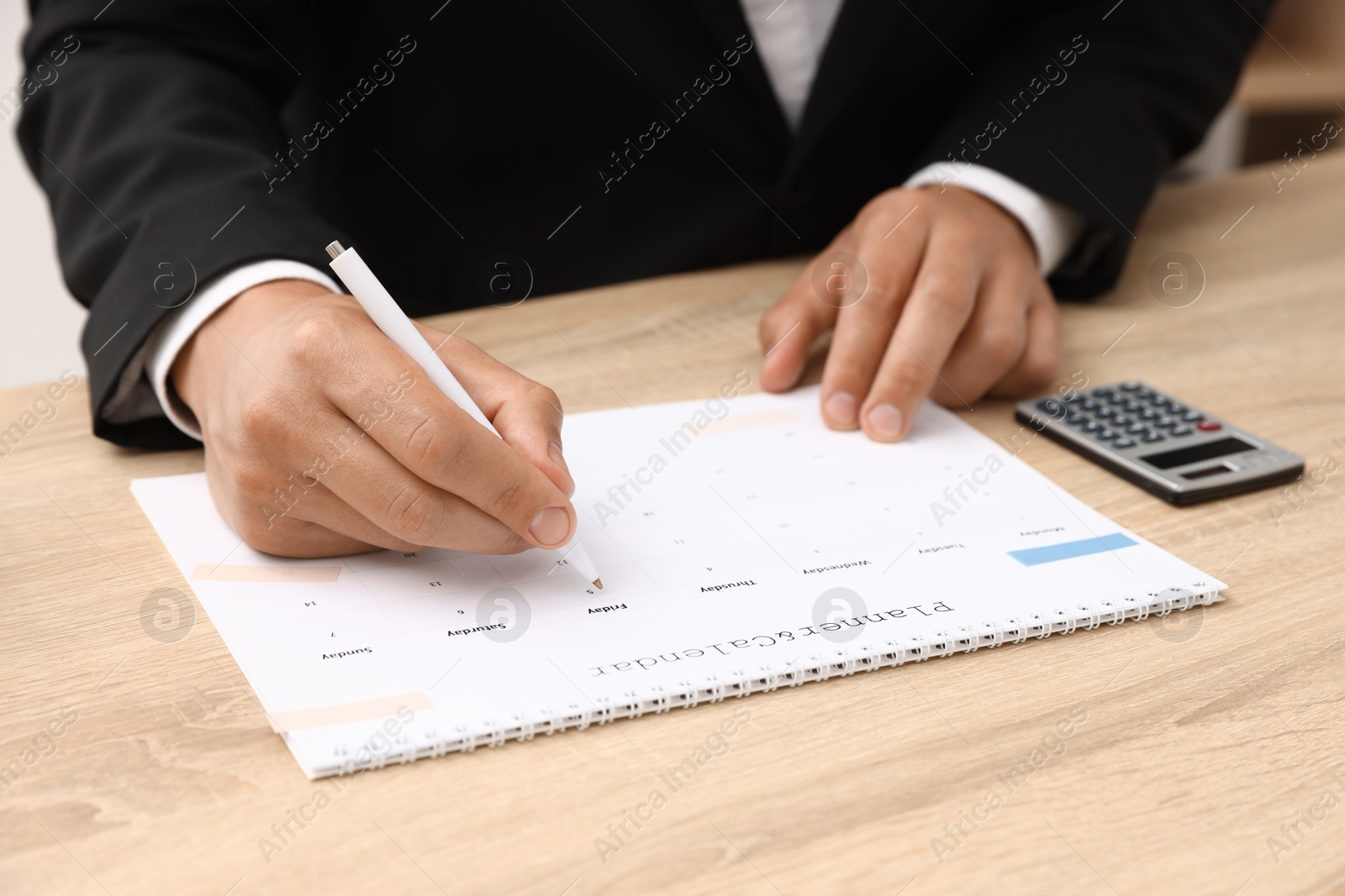 Man using business planner at wooden table in office, closeup Photo of Man using business planner at wooden table in office, closeup
