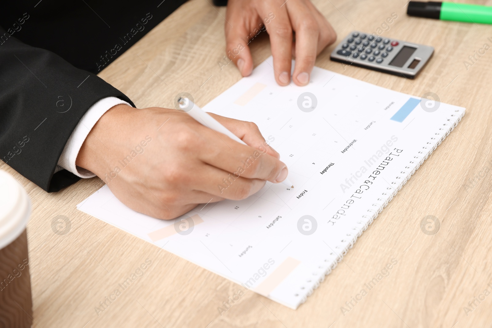 Man using business planner at wooden table in office, closeup Photo of Man using business planner at wooden table in office, closeup