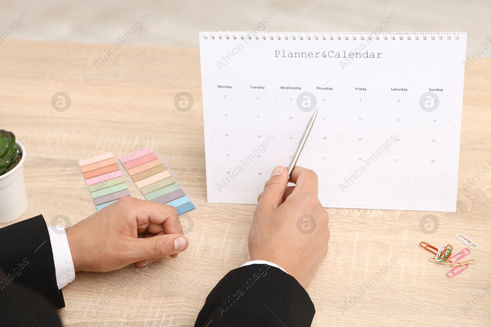 Man using business planner at wooden table in office, closeup Photo of Man using business planner at wooden table in office, closeup