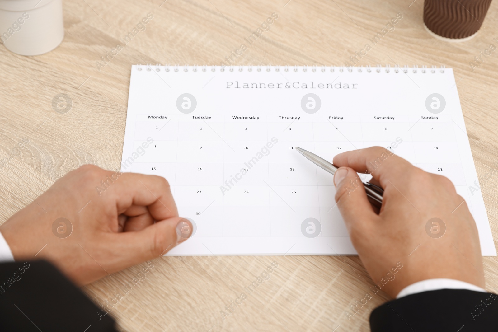 Man using business planner at wooden table in office, closeup Photo of Man using business planner at wooden table in office, closeup