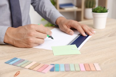 Photo of Business planning. Man using calendar at wooden table in office, closeup