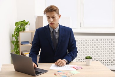 Photo of Business planning. Man with calendar and laptop at wooden table in office