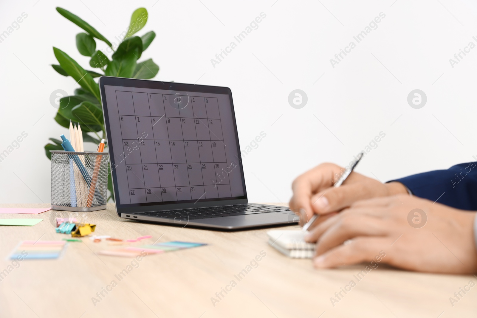 Man using business planner at wooden table in office, closeup Photo of Man using business planner at wooden table in office, closeup