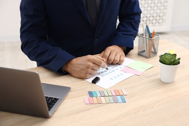 Photo of Business planning. Man with calendar at wooden table in office, closeup
