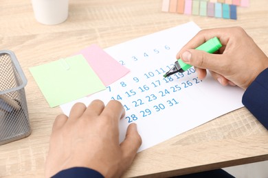Photo of Business planning. Man with calendar at wooden table in office, closeup