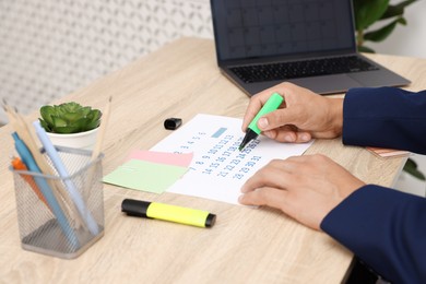 Photo of Business planning. Man with calendar at wooden table in office, closeup