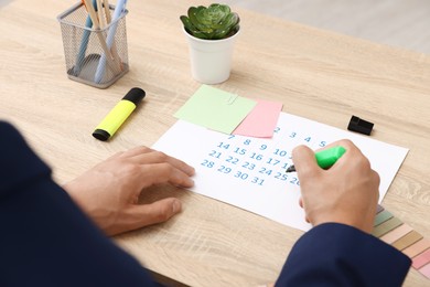Photo of Business planning. Man with calendar at wooden table in office, closeup