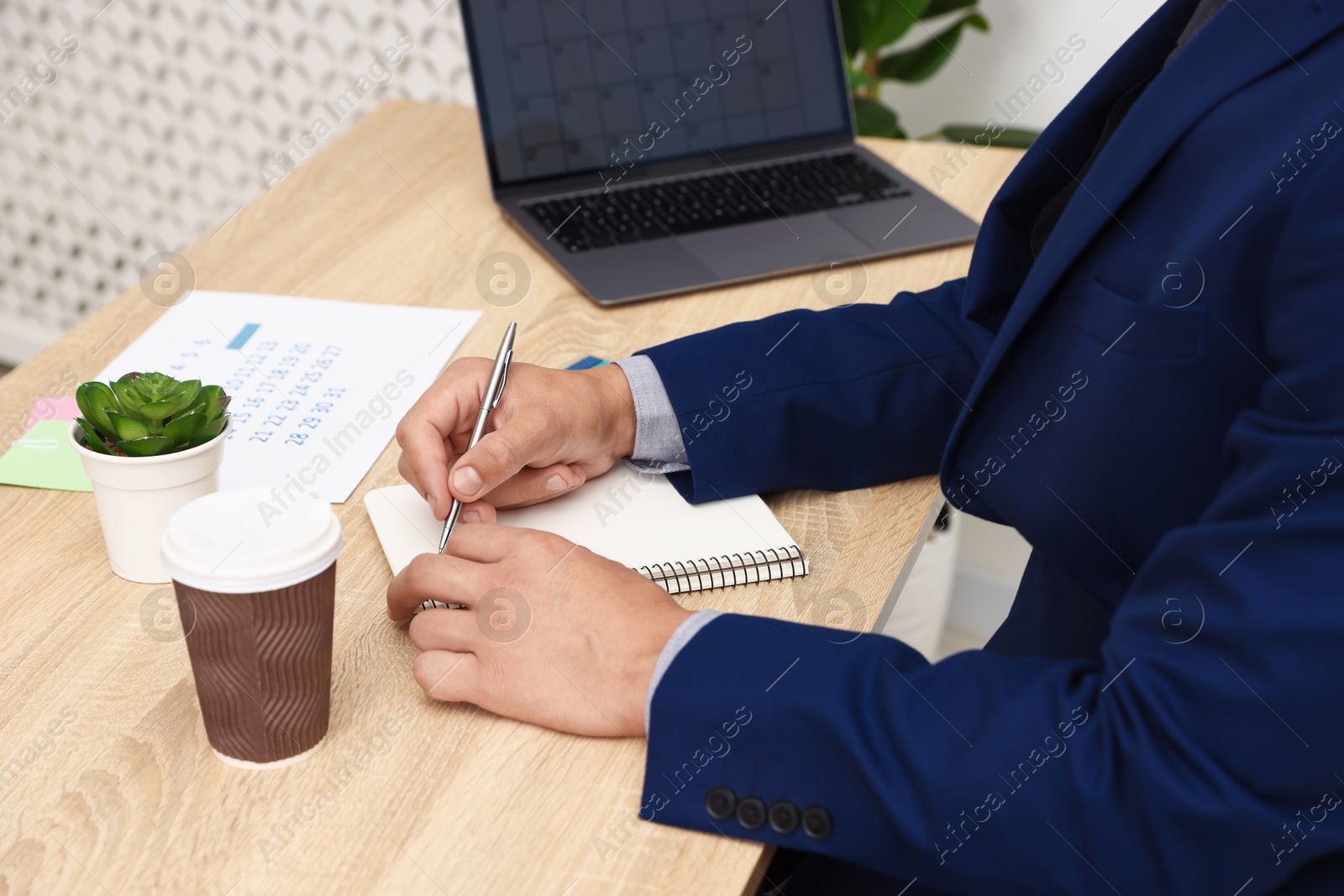 Man using business planner at wooden table in office, closeup Photo of Man using business planner at wooden table in office, closeup