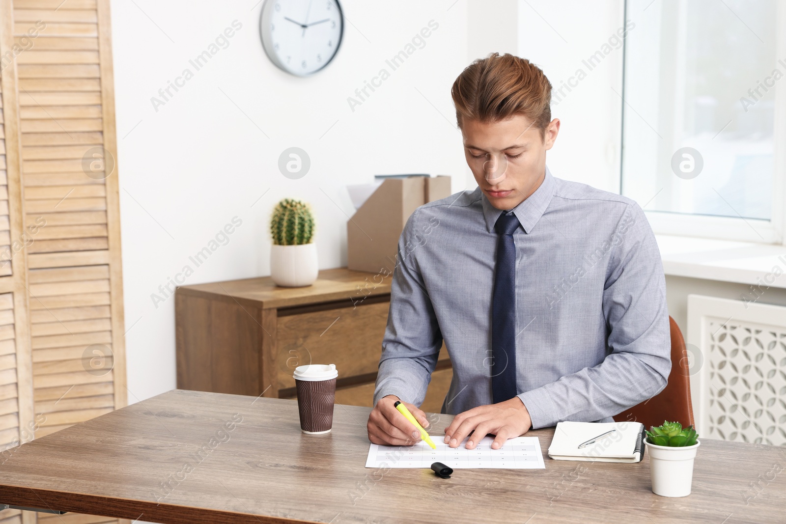 Business planning. Man with calendar at wooden table in office Photo of Business planning. Man with calendar at wooden table in office