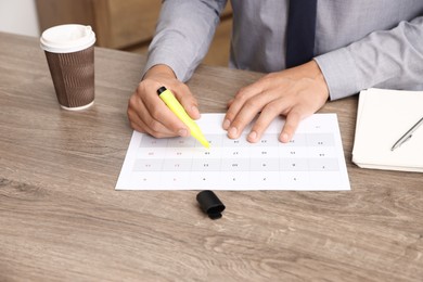 Photo of Business planning. Man with calendar at wooden table in office, closeup