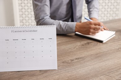 Photo of Man using business planner at wooden table in office, selective focus