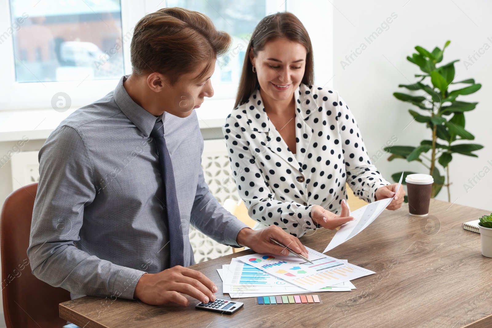 Business planning. Woman and man with calendar and documents at wooden table in office Photo of Business planning. Woman and man with calendar and documents at wooden table in office