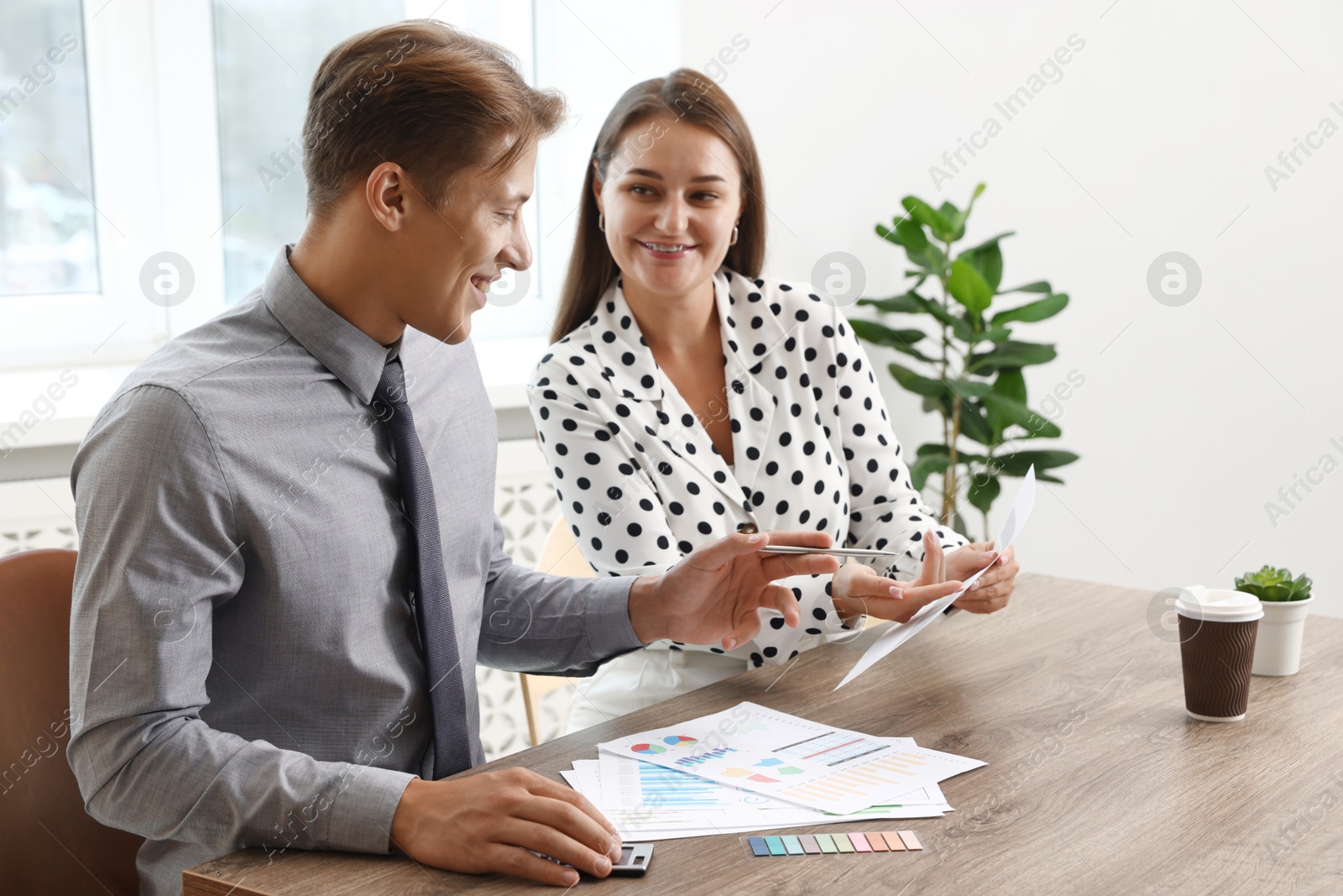 Business planning. Woman and man with calendar and documents at wooden table in office Photo of Business planning. Woman and man with calendar and documents at wooden table in office