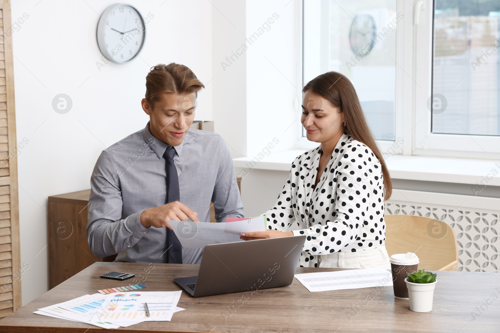 Photo of Business planning. Woman and man with calendar and documents at wooden table in office