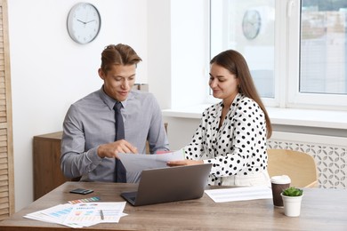 Photo of Business planning. Woman and man with calendar and documents at wooden table in office