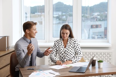 Photo of Business planning. Woman and man with calendar and documents at wooden table in office