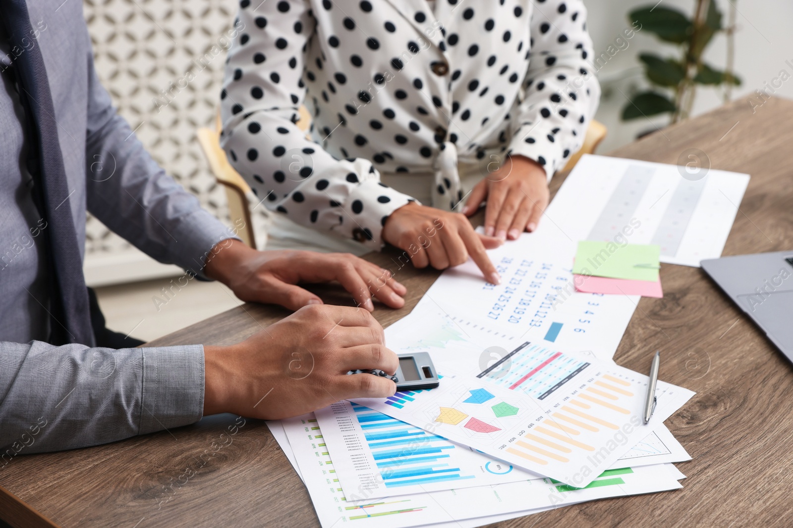 Business planning. Woman and man with calendar and documents at wooden table in office, closeup Photo of Business planning. Woman and man with calendar and documents at wooden table in office, closeup