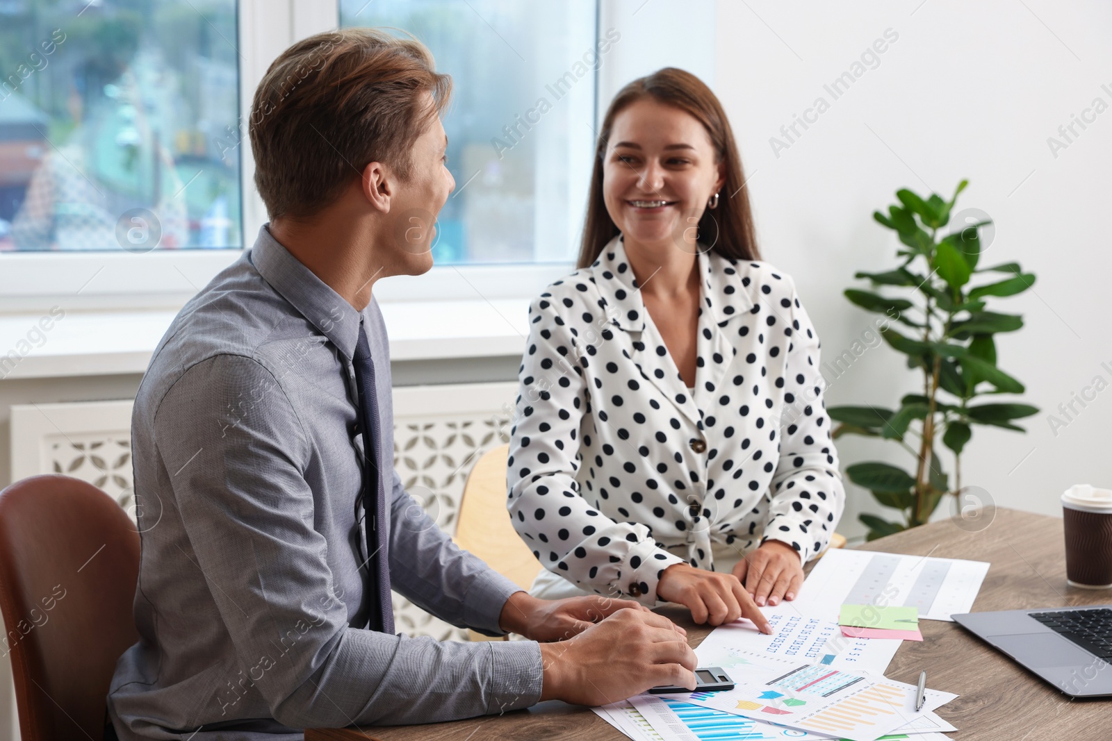 Business planning. Woman and man with calendar and documents at wooden table in office Photo of Business planning. Woman and man with calendar and documents at wooden table in office