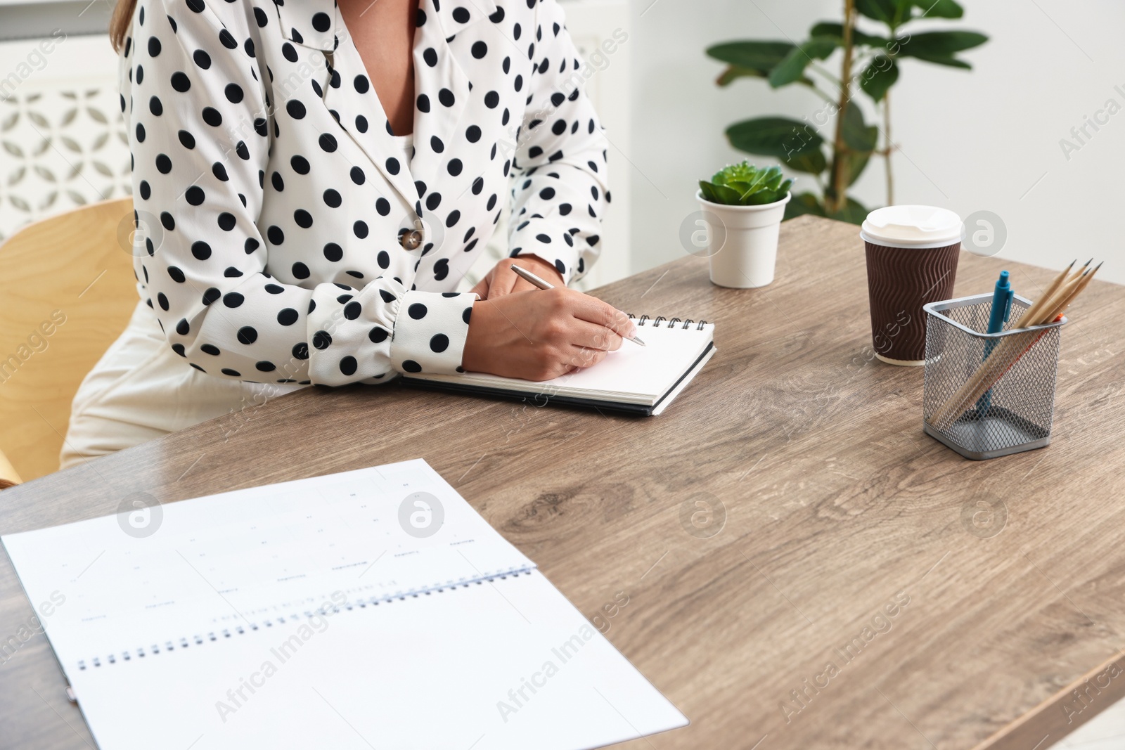 Woman using business planner at wooden table in office, closeup Photo of Woman using business planner at wooden table in office, closeup