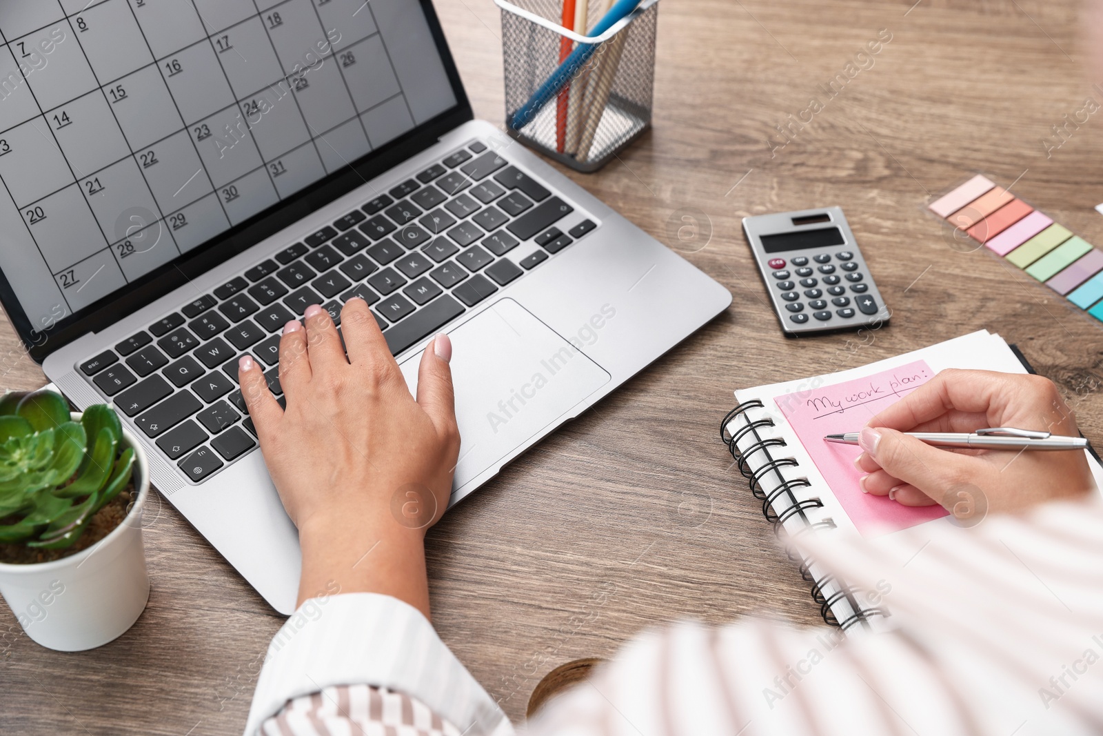 Woman using business planner and laptop at wooden table in office, closeup Photo of Woman using business planner and laptop at wooden table in office, closeup