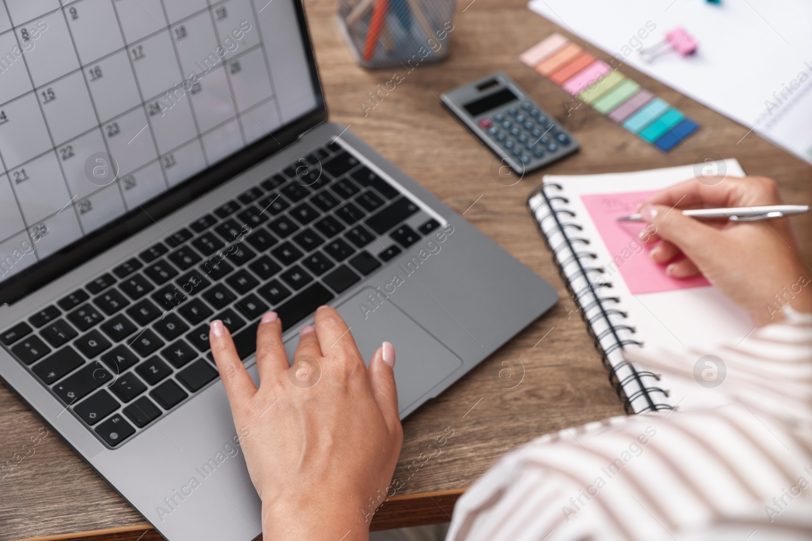 Woman using business planner and laptop at wooden table in office, closeup Photo of Woman using business planner and laptop at wooden table in office, closeup