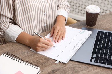 Photo of Business planning. Woman with calendar at wooden table in office, closeup