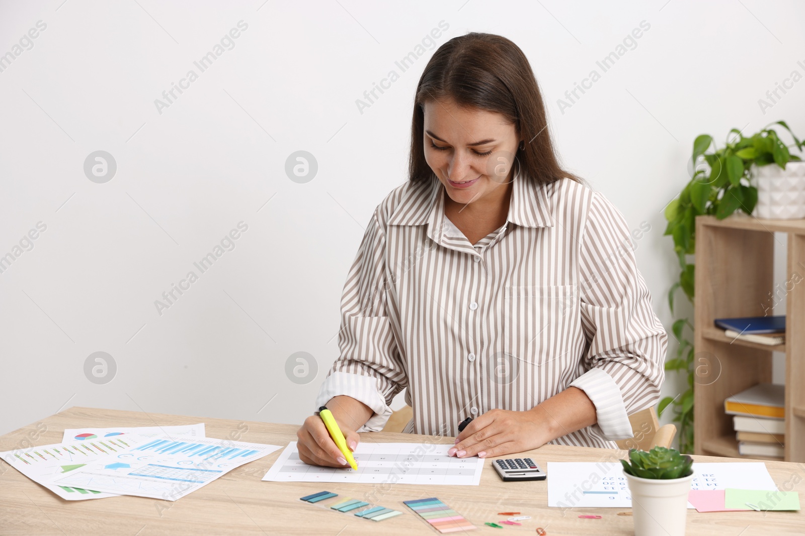 Business planning. Woman with calendar at wooden table in office Photo of Business planning. Woman with calendar at wooden table in office