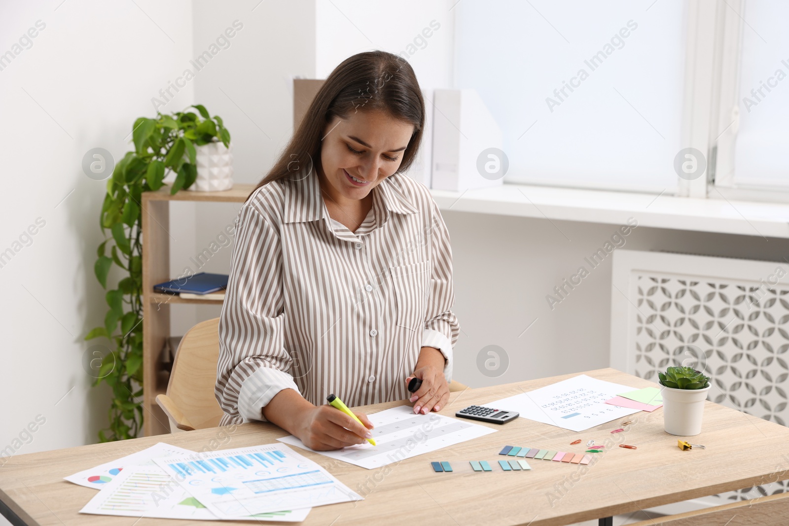 Business planning. Woman with calendar at wooden table in office Photo of Business planning. Woman with calendar at wooden table in office