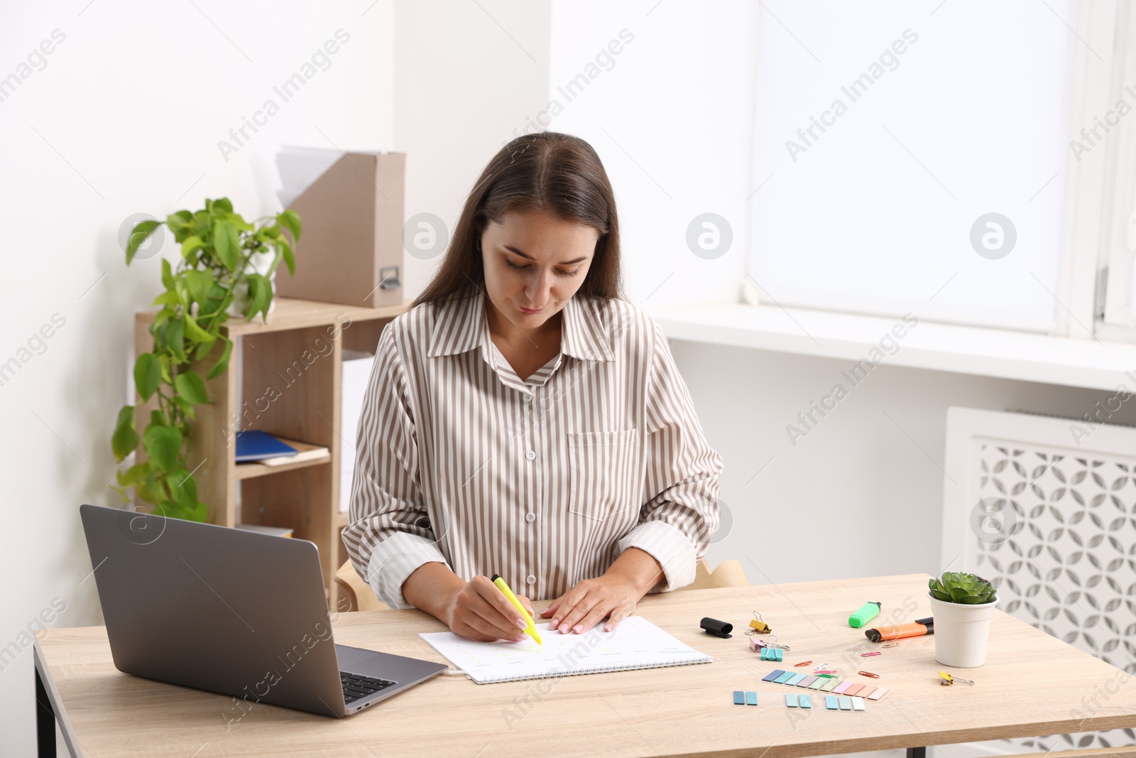 Business planning. Woman with calendar at wooden table in office Photo of Business planning. Woman with calendar at wooden table in office