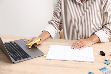 Photo of Business planning. Woman with calendar and laptop at wooden table in office, closeup