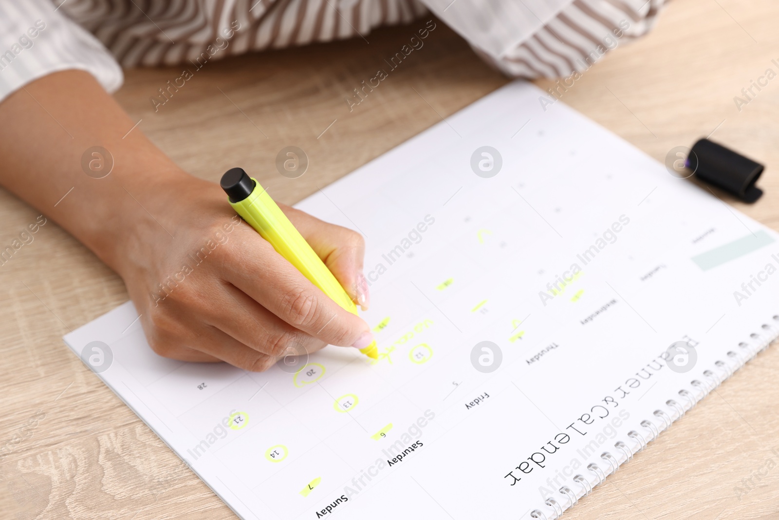 Photo of Business planning. Woman with calendar at wooden table in office, closeup