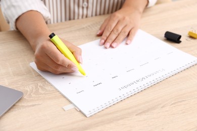 Photo of Business planning. Woman with calendar at wooden table in office, closeup
