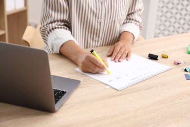 Photo of Business planning. Woman with calendar at wooden table in office, closeup
