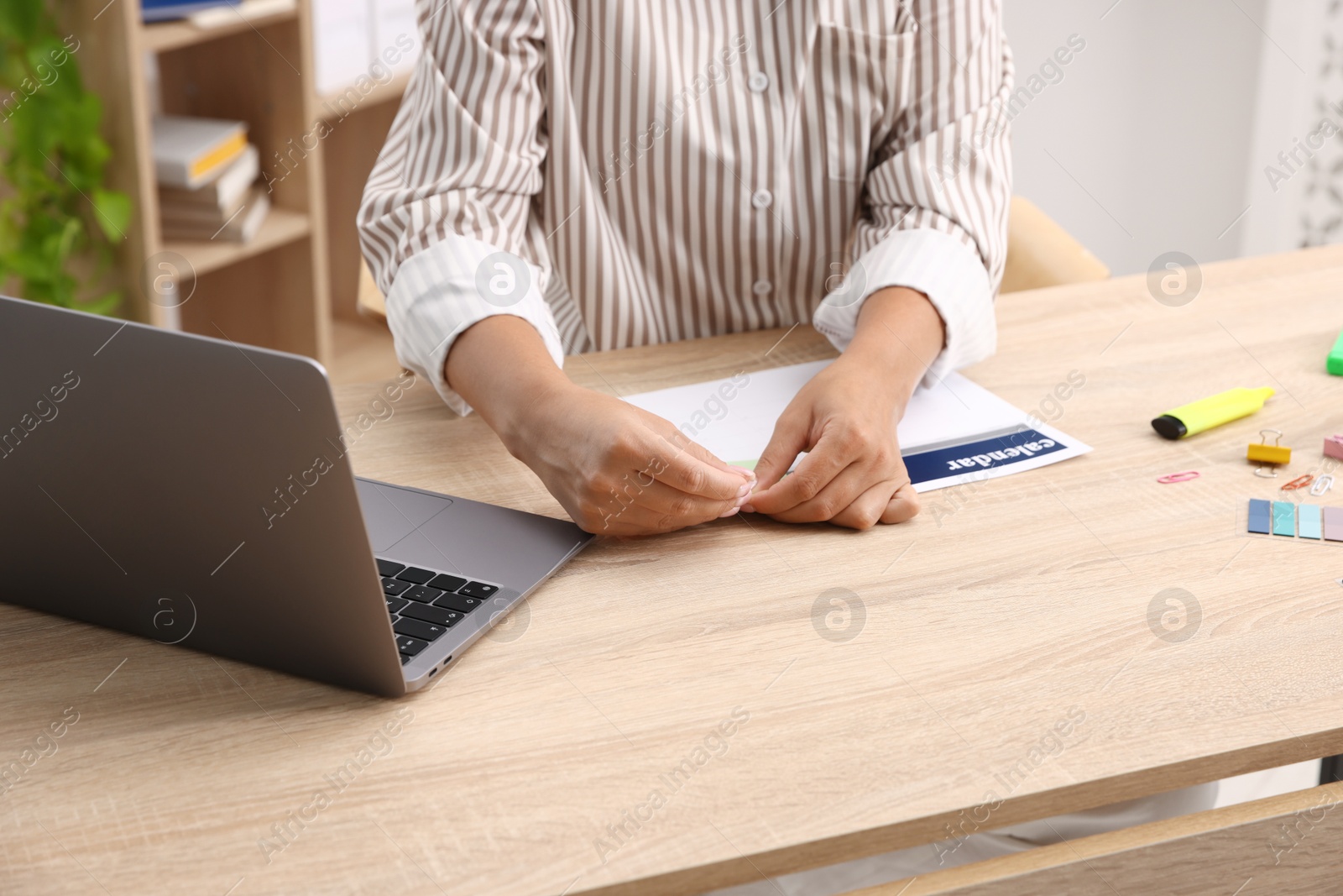 Business planning. Woman using calendar at wooden table in office, closeup Photo of Business planning. Woman using calendar at wooden table in office, closeup