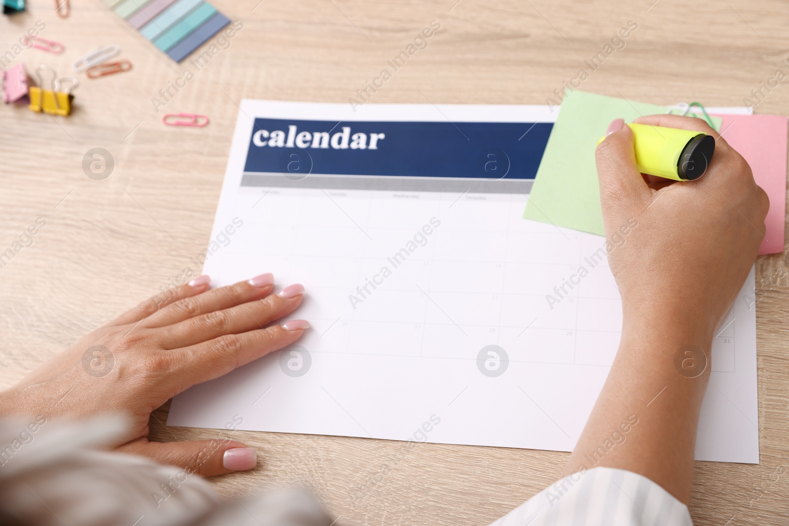 Photo of Business planning. Woman using calendar at wooden table in office, closeup