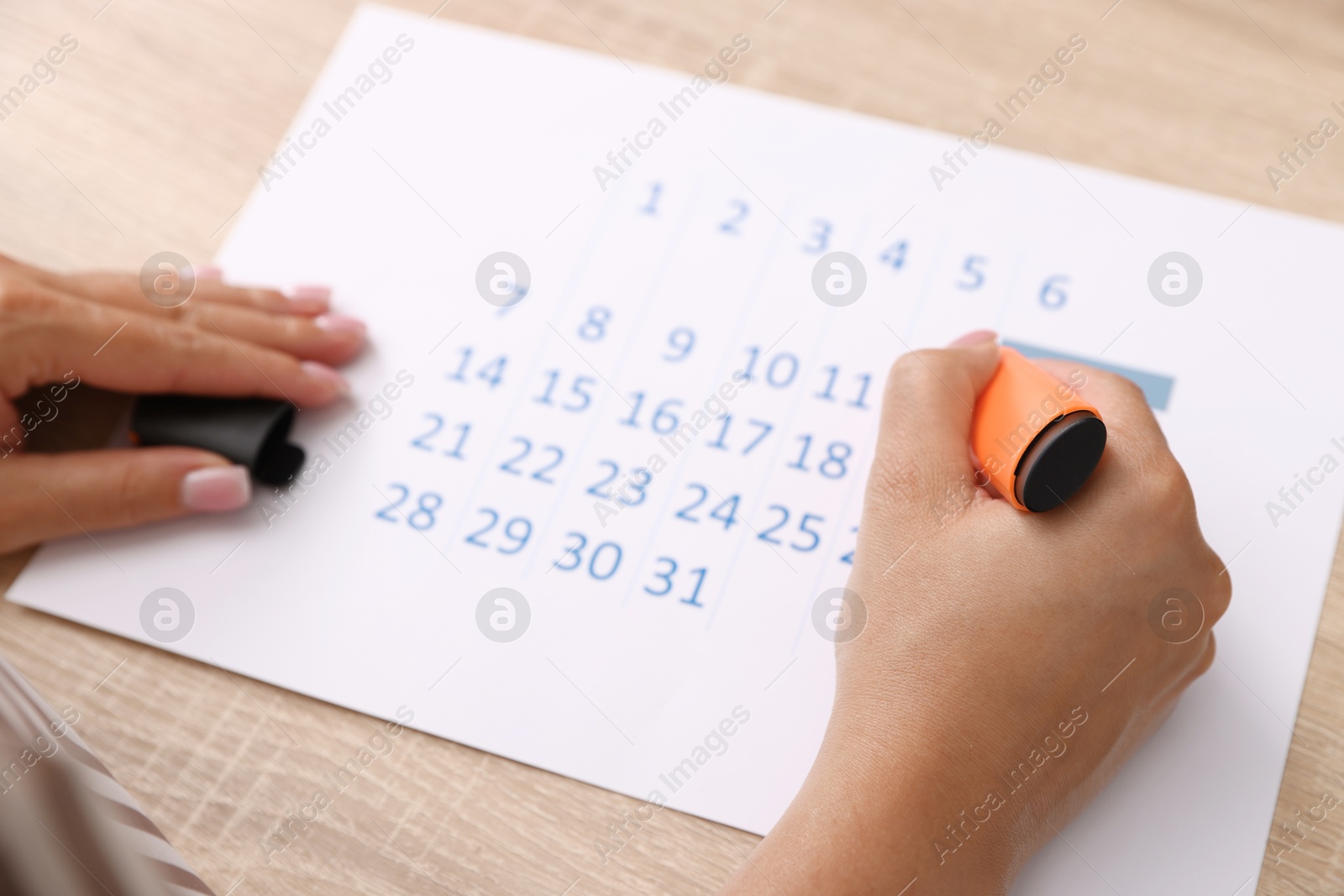 Photo of Business planning. Woman using calendar at wooden table in office, closeup