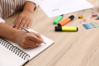 Photo of Woman using business planner at wooden table in office, closeup
