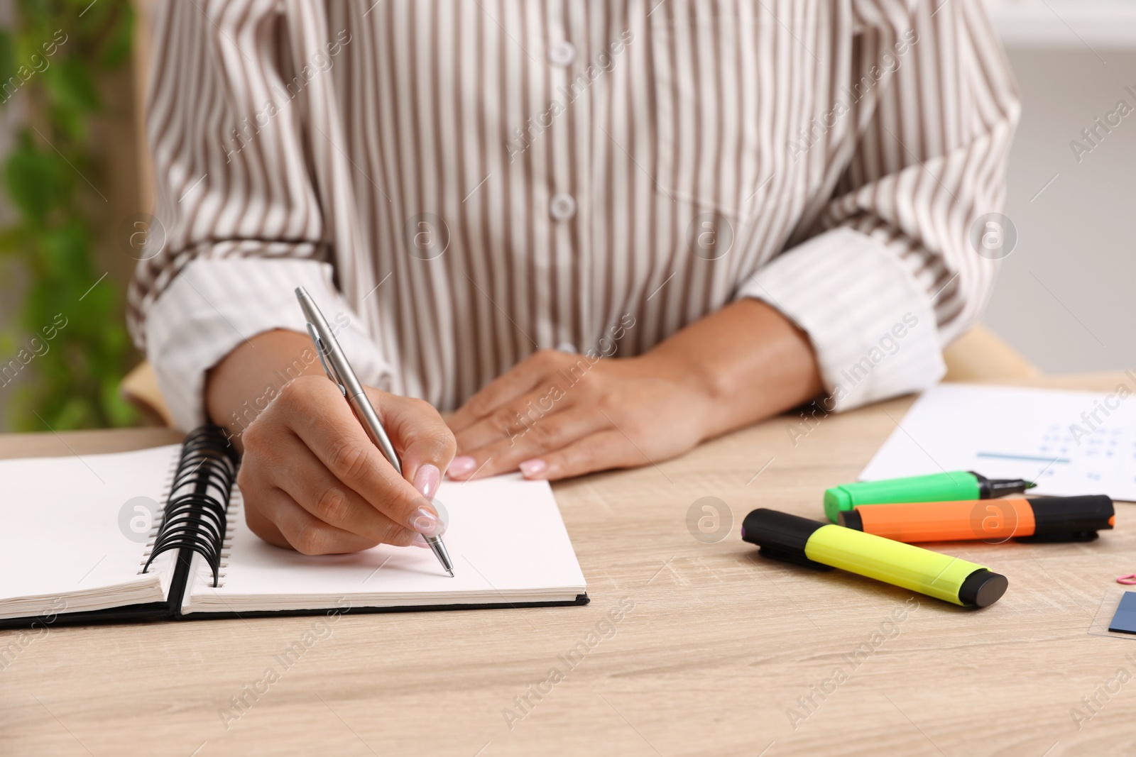 Photo of Woman using business planner at wooden table in office, closeup