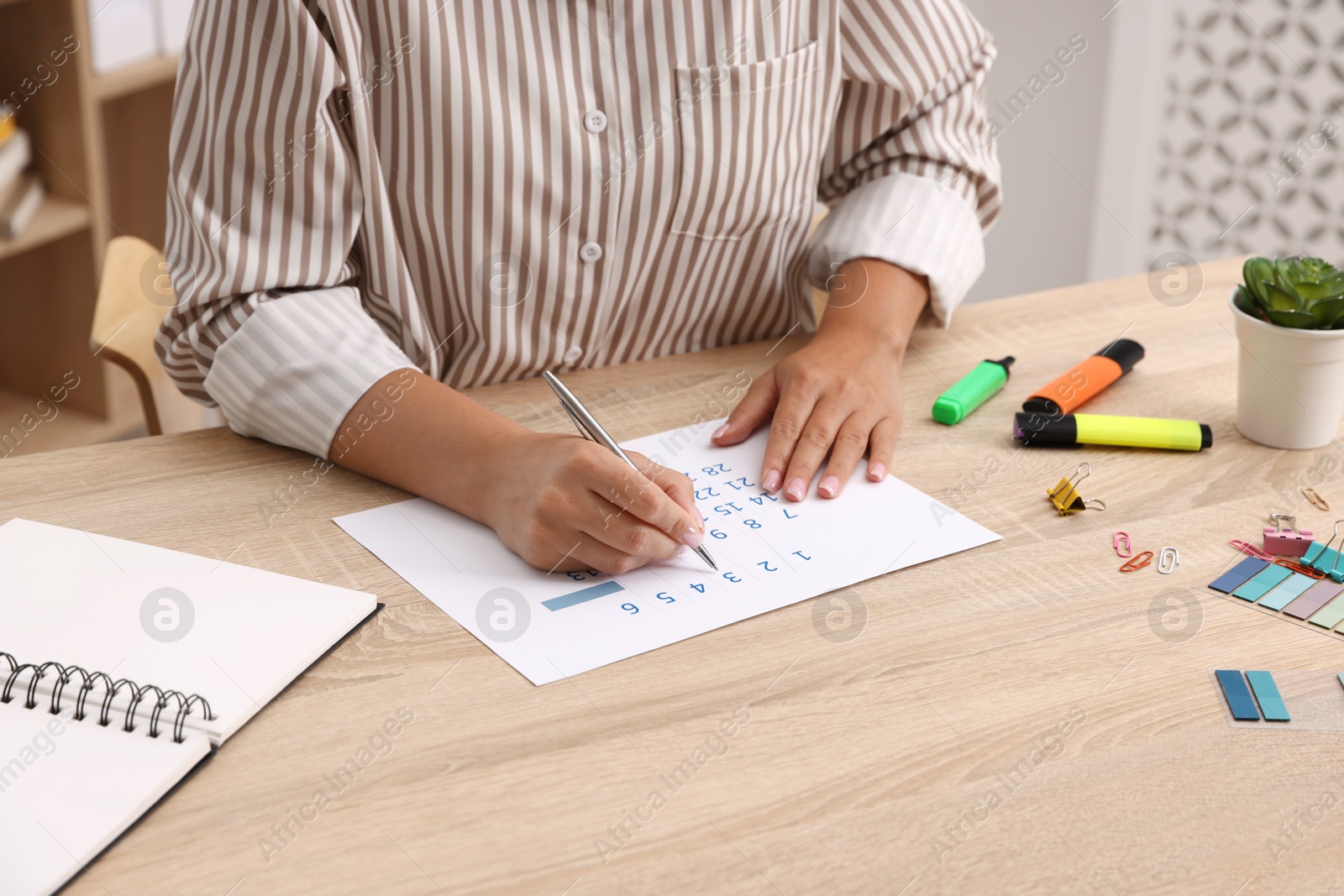 Business planning. Woman using calendar at wooden table in office, closeup Photo of Business planning. Woman using calendar at wooden table in office, closeup
