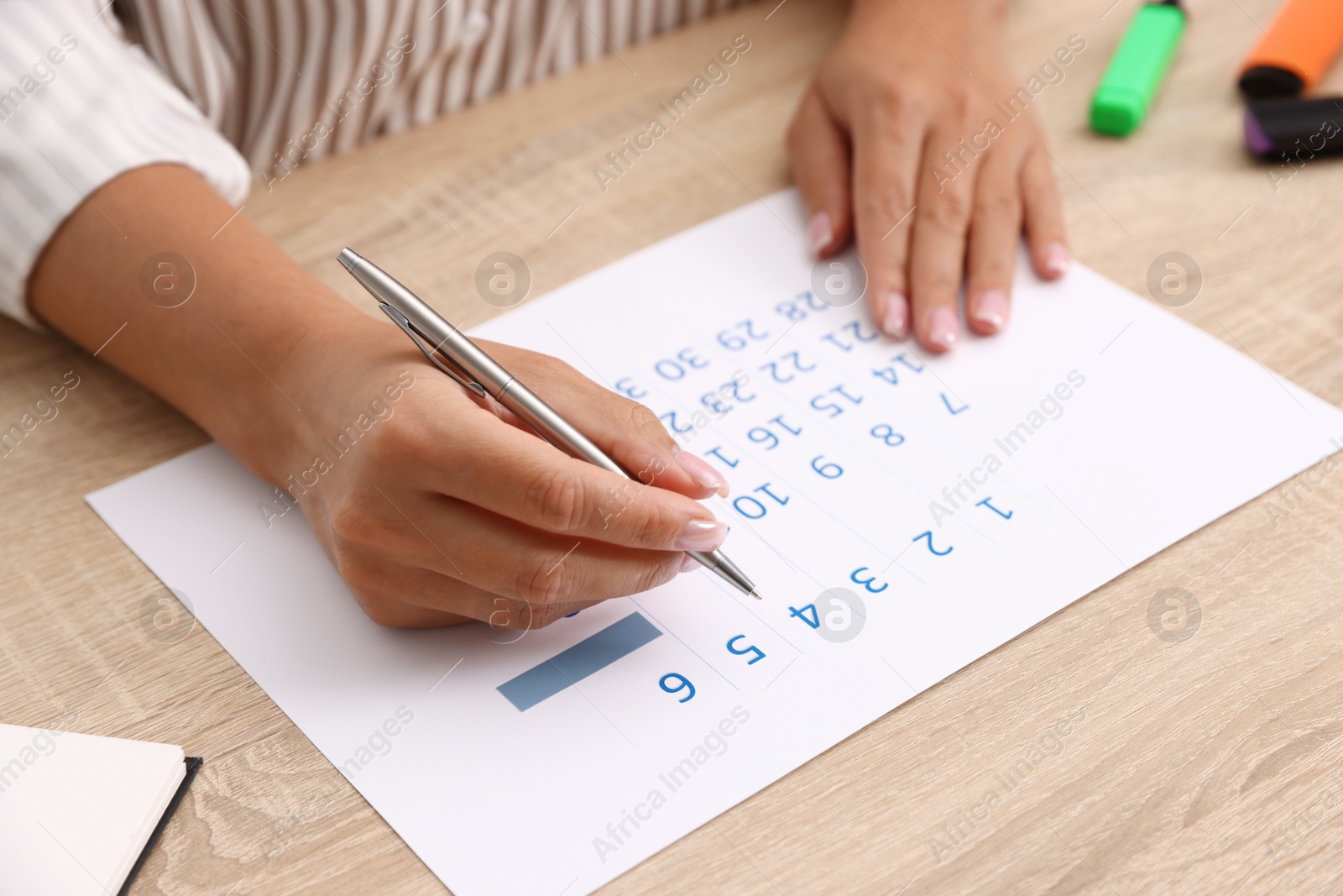 Photo of Business planning. Woman using calendar at wooden table in office, closeup