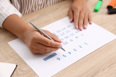 Photo of Business planning. Woman using calendar at wooden table in office, closeup