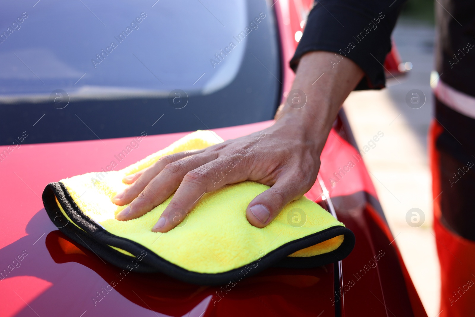 Man wiping car hood with yellow microfiber rag outdoors, closeup Photo of Man wiping car hood with yellow microfiber rag outdoors, closeup