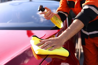 Photo of Man wiping car hood with yellow microfiber rag outdoors, closeup