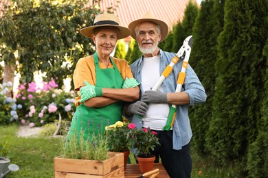 Photo of Happy senior couple in gloves and hats in garden
