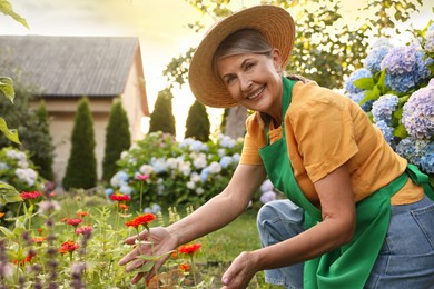 Photo of Smiling senior woman in hat and apron in garden