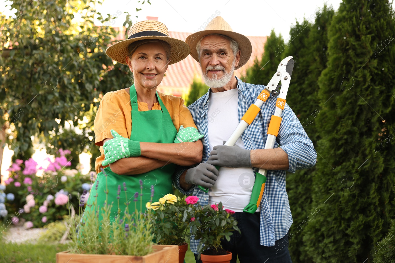 Photo of Happy senior couple in gloves and hats in garden